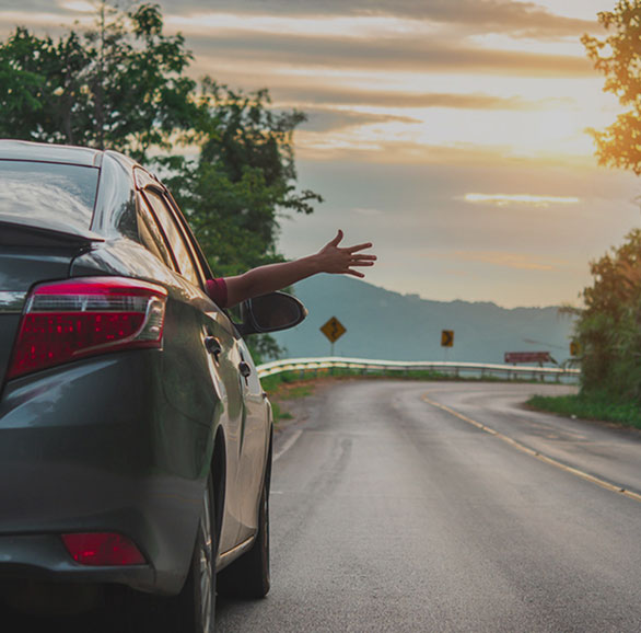 Car driving down road with passengers arm out window