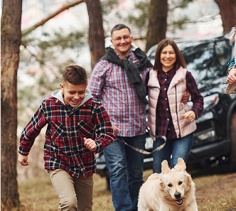 family with a dog in front of a car