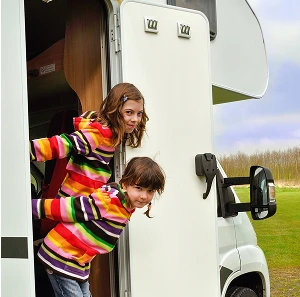 two young girls leaning out of a RV