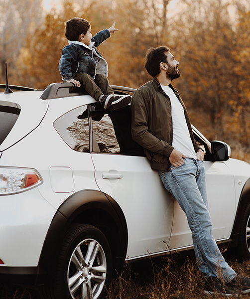 father and son leaning on car